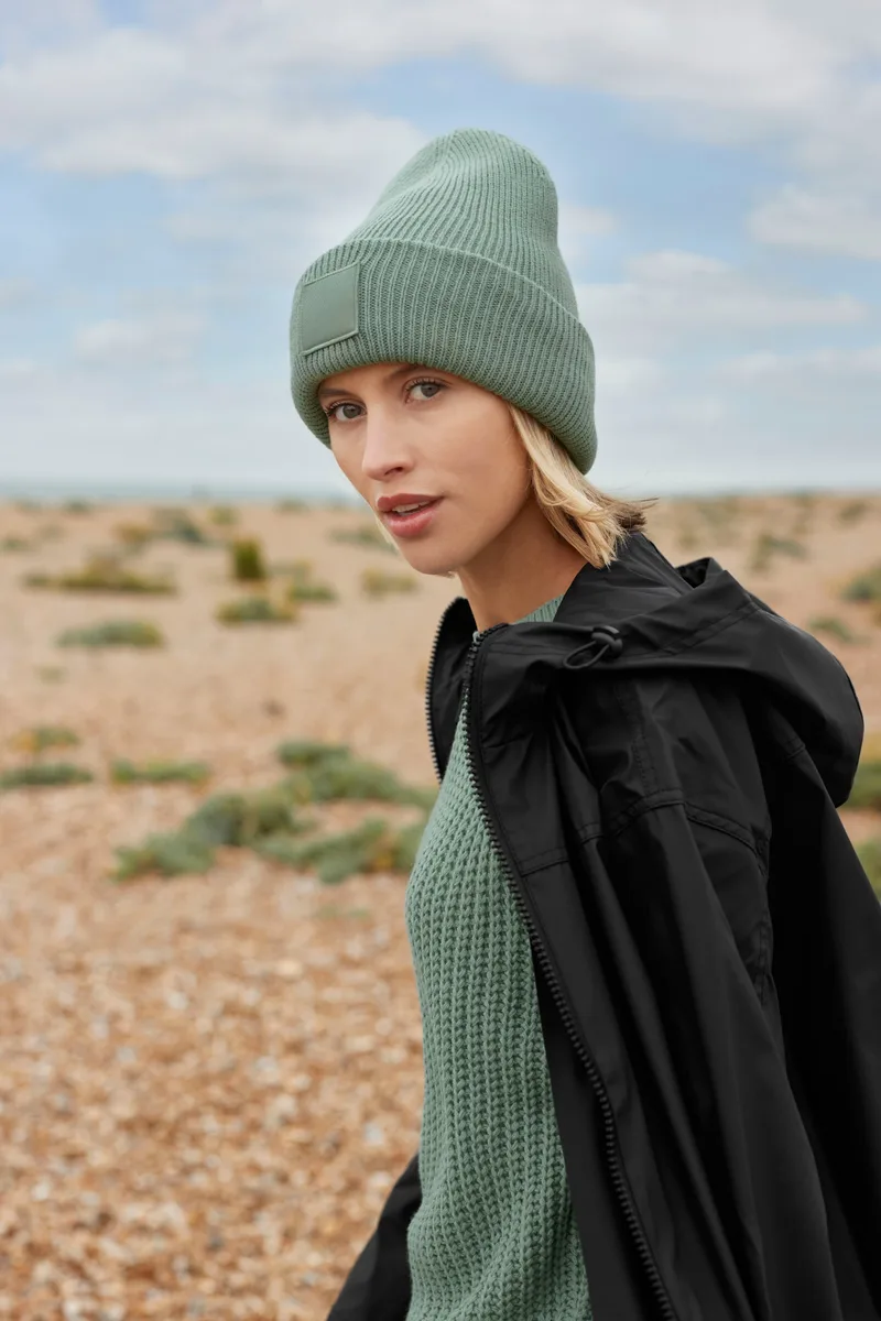 Frau mit grüner Beechfield-Beanie in den Dünen (Hochformat)