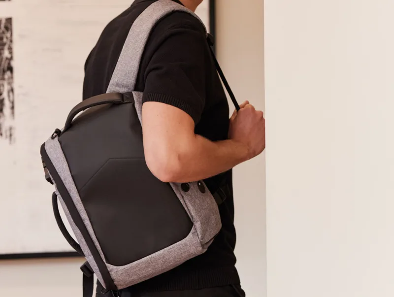 Mann in schwarzem T-Shirt mit grau-schwarzem Rucksack über der Schulter, Ausschnitt ohne Gesicht. Titelbild der Corporate-Kollektion.