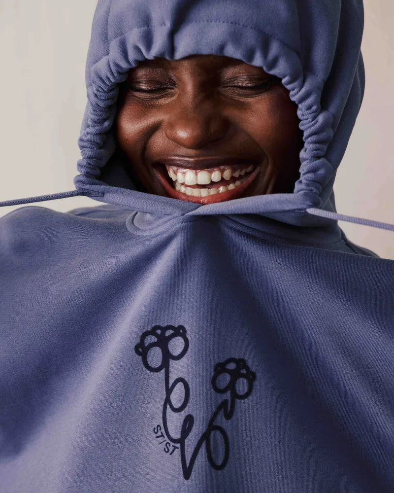 Lachende Person mit aufgesetzter Kapuze eines bestickten Hoodies (Hochformat)
