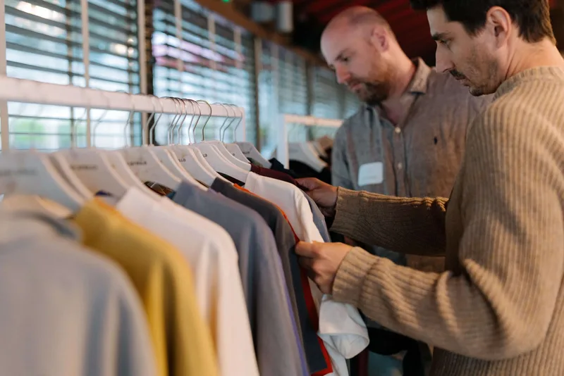 Zwei Männer begutachten Kollektion an einer Kleiderstange im Showroom