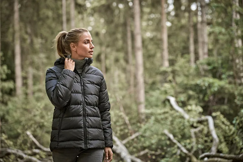 Frau in dunkler Steppjacke im Wald (ca. 42 MB)