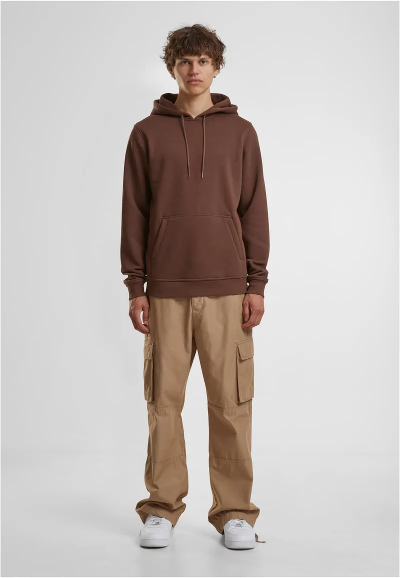 Mann in braunem Heavy Hoody und Cargohose, ganzer Körper, grauer Studiohintergrund
