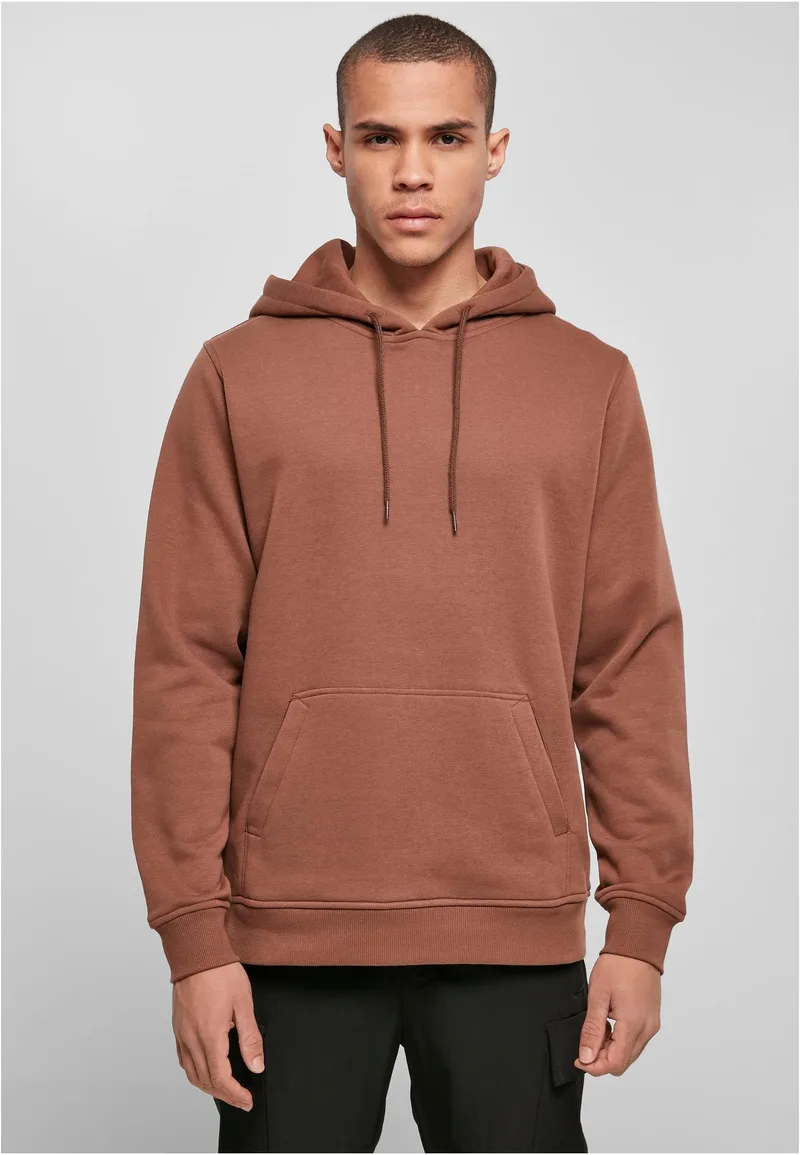 Mann in rostbraunem Heavy Hoody, grauer Studiohintergrund