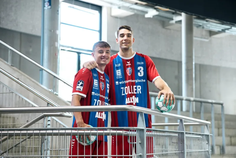 Zwei Handballer in Vereinstrikots auf einer Stadiontreppe