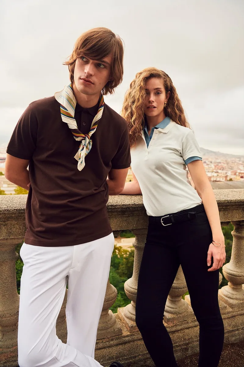 Paar in Clique-T-Shirt und Polo an einer Steinbalustrade im Süden (Hochformat)