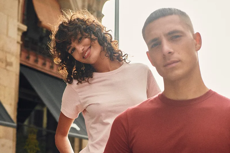 Junges Paar in rosa und rotem Clique-T-Shirt in einer Altstadtgasse