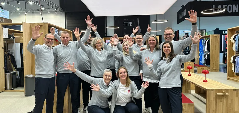 ID-Team in grauen Sweatshirts jubelt auf dem Messestand