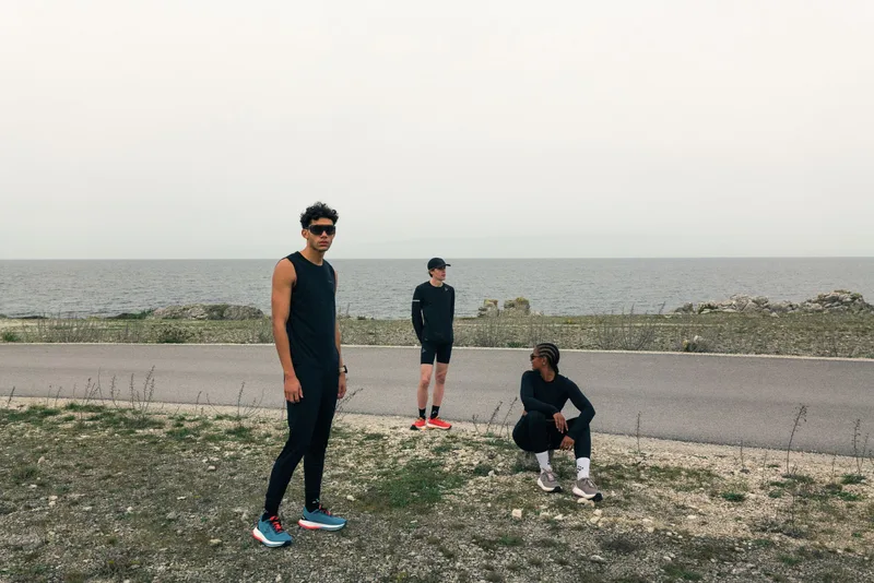 Drei Läufer in dunkler Craft-Teamwear auf einem Küstenweg am Meer (Bild der Teamwear-Seite)
